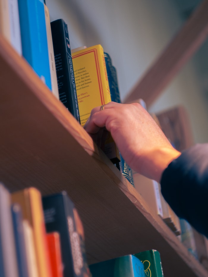 A student reaching for a book on a library shelf